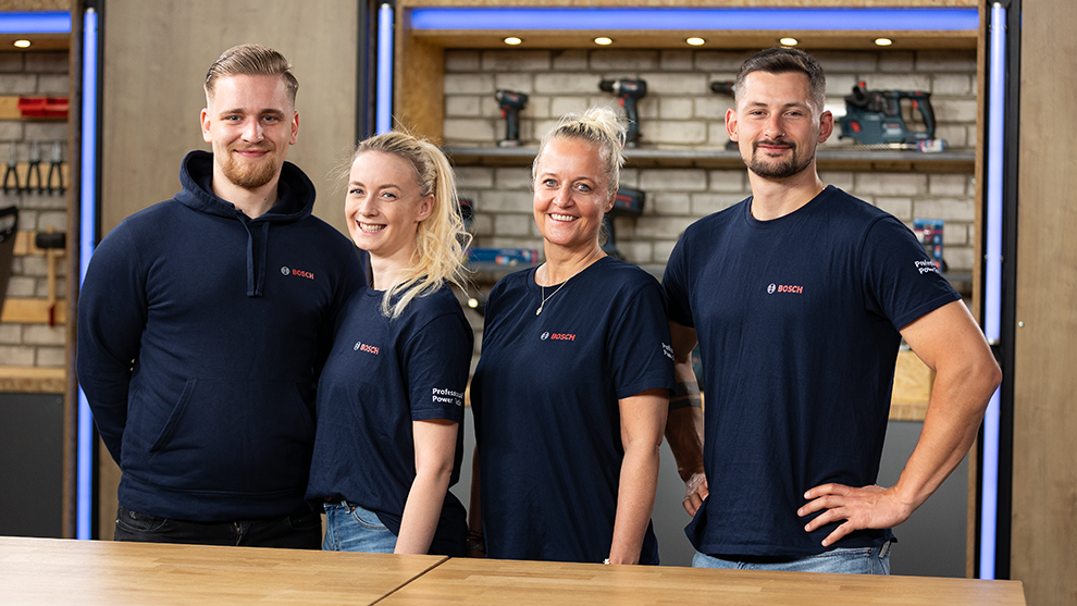 Four people in Bosch T-shirts are smiling in front of a workshop.