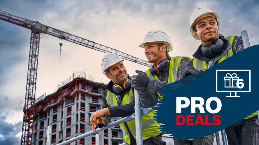 Drei Bauarbeiter mit Helmen und Warnwesten stehen vor einem Baugerüst.