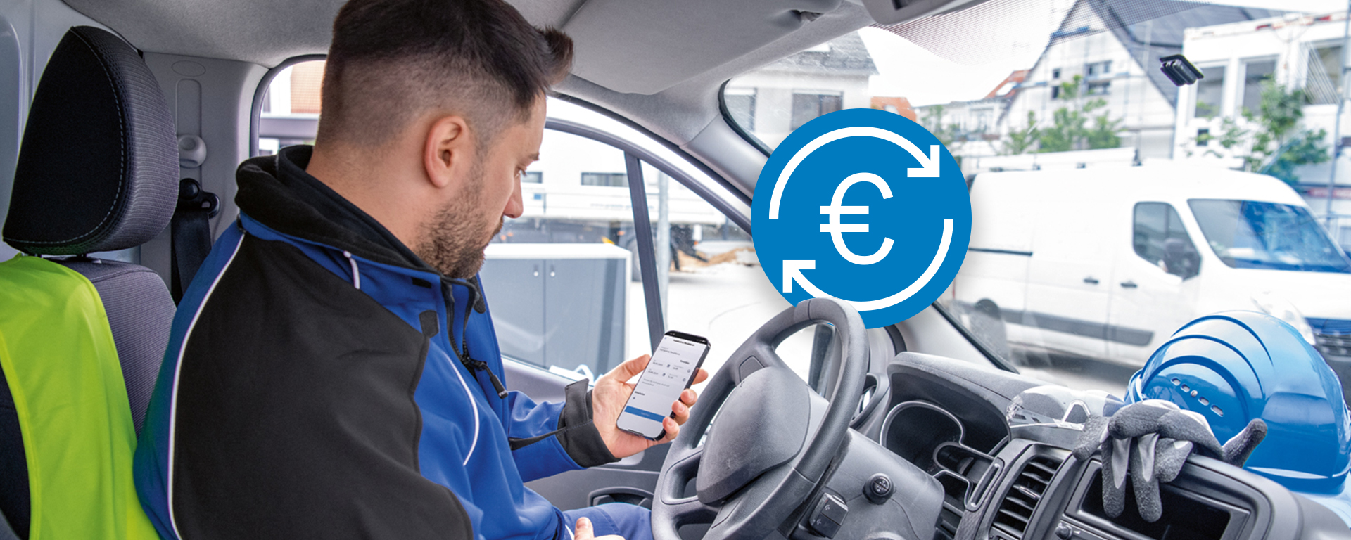 Ein Handwerker sitzt in einem Fahrzeug und schaut auf sein Smartphone. Neben ihm liegen ein blauer Helm und Arbeitshandschuhe. Im Hintergrund sind andere Fahrzeuge und Gebäude zu sehen. Die Stimmung wirkt konzentriert und geschäftig.