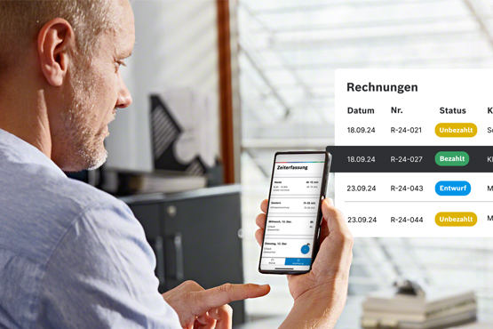 Die beste Handwerkersoftware im Vergleich 2025: Der ultimative Guide für Handwerker Ein Mann mit kurzen Haaren schaut auf ein Smartphone, das Rechnungen anzeigt. Im Hintergrund ist ein Büro.