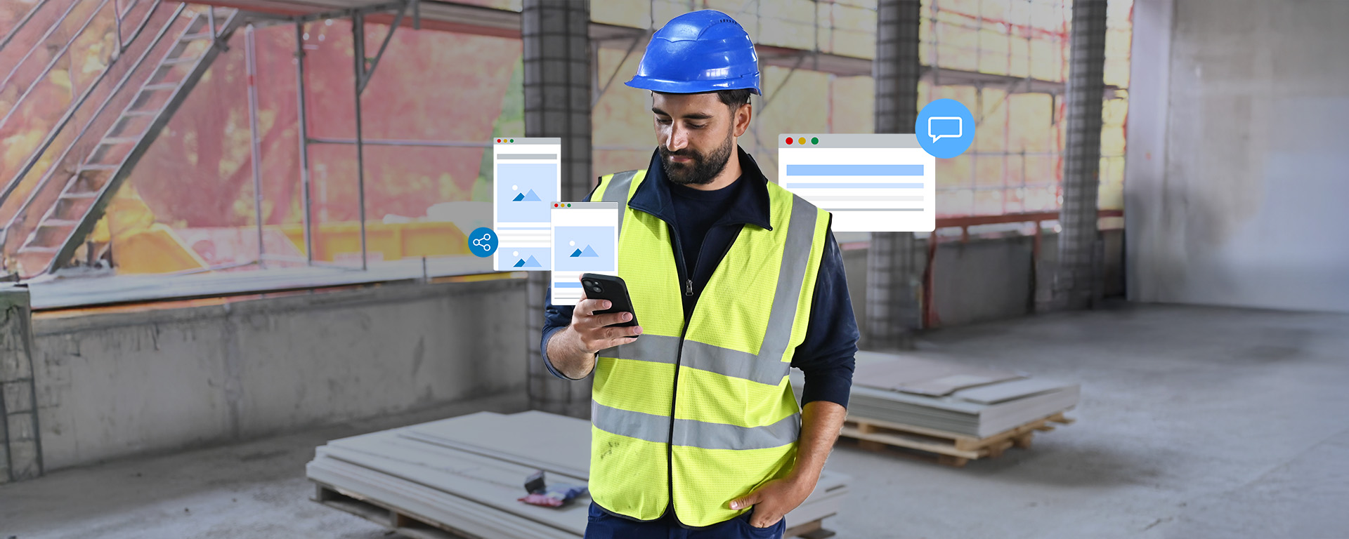 Ein Mann in einem gelben Sicherheitswesten und blauem Helm schaut auf sein Smartphone in einer Baustelle. Im Hintergrund sind Baustellenmaterialien und Baustellenstrukturen sichtbar.