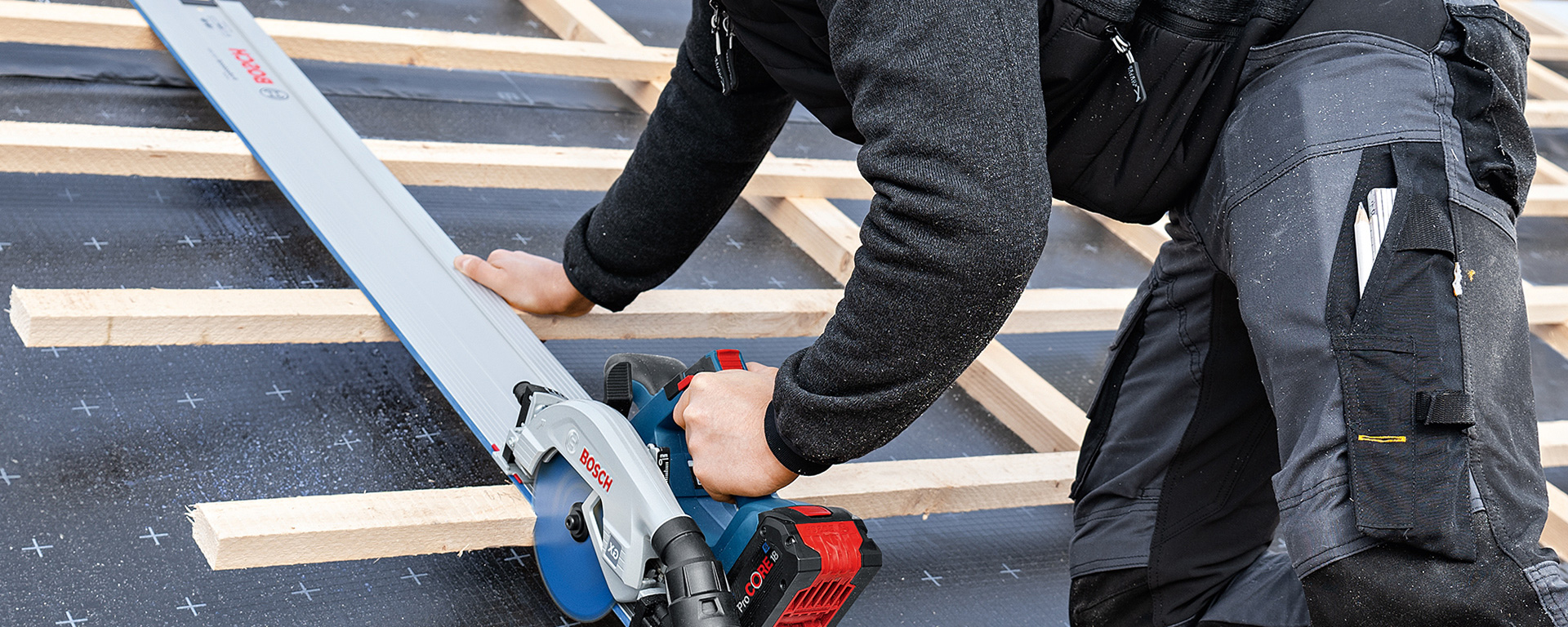 A craftsman uses a Bosch Professional cordless circular saw on wooden boards.