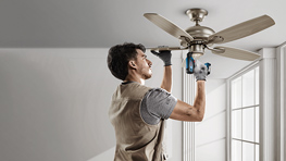 Ein Arbeiter installiert einen Deckenventilator mit einem blauen Bosch Werkzeug.