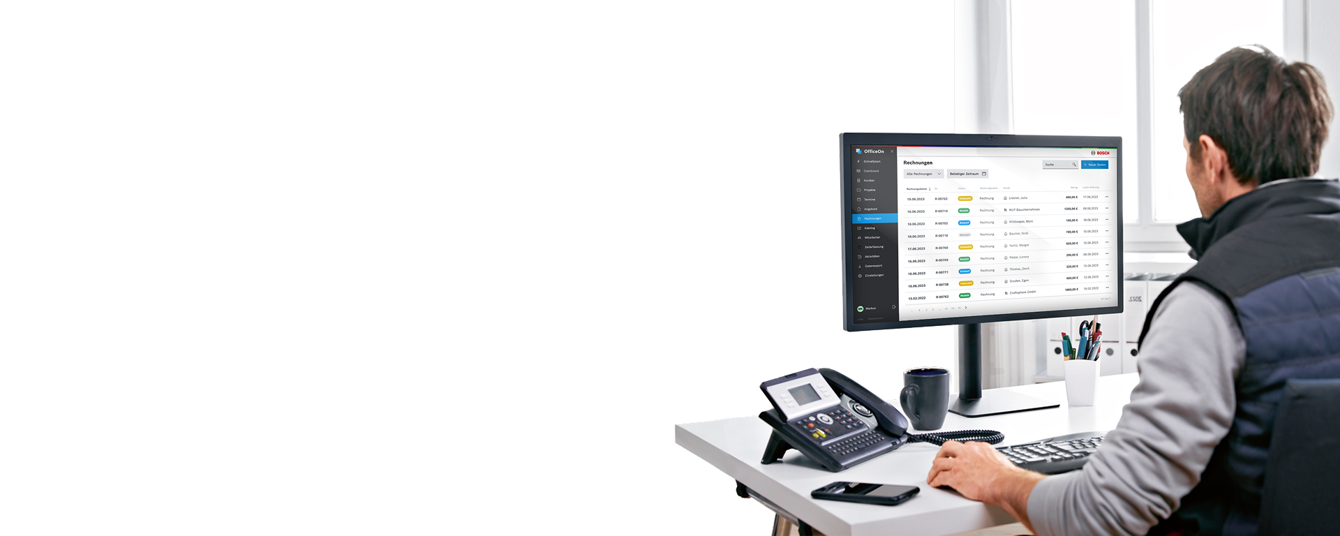 Ein Mann sitzt an einem Schreibtisch und arbeitet am Computer.